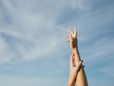 A person's hands reaching towards the sky during stretching.