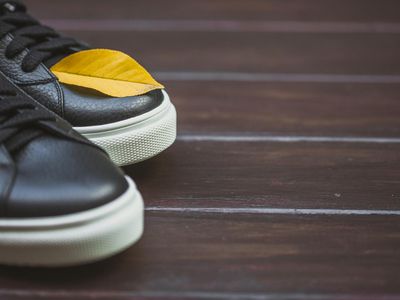 Close up of sneakers on a dark wooden floor.