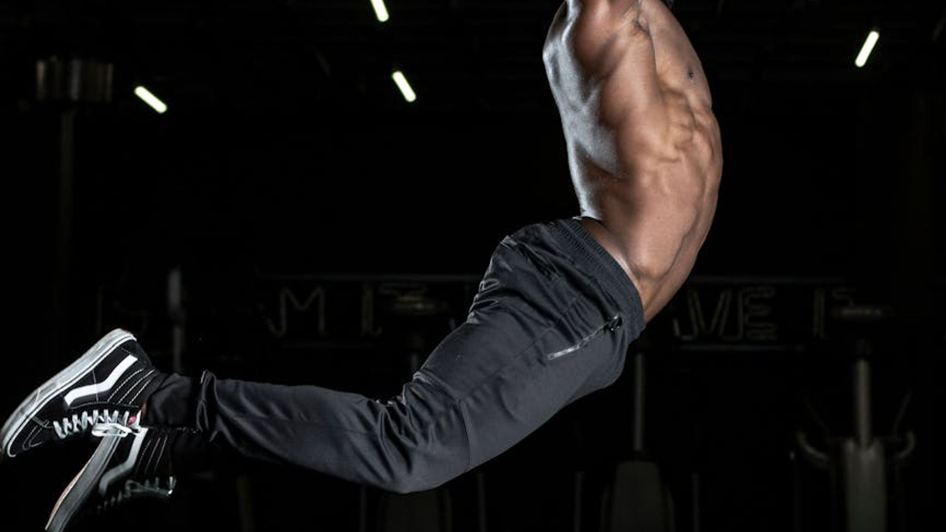 Person doing dynamic cardio movements in a dark studio.